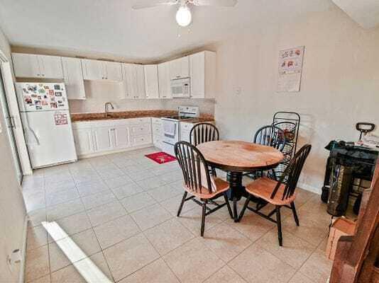 A kitchen with white cabinets, tile flooring, and a round wooden dining table with chairs — 2168 White Pine Circle # D, FL 33415, FL