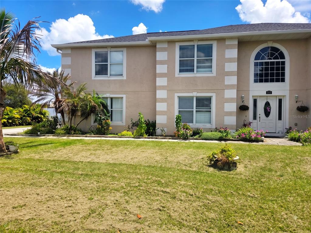 A two-story tan house with white trim and a front entrance featuring a arched window — 321 LAKE HILLS LANE, EAGLE LAKE, FL