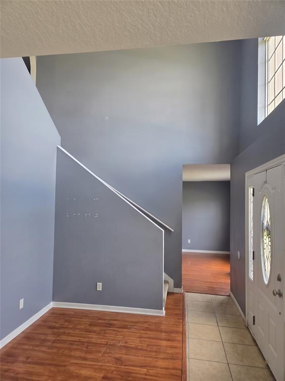 An entryway with a high ceiling, a staircase, wood flooring, and a white front door — 321 LAKE HILLS LANE, EAGLE LAKE, FL