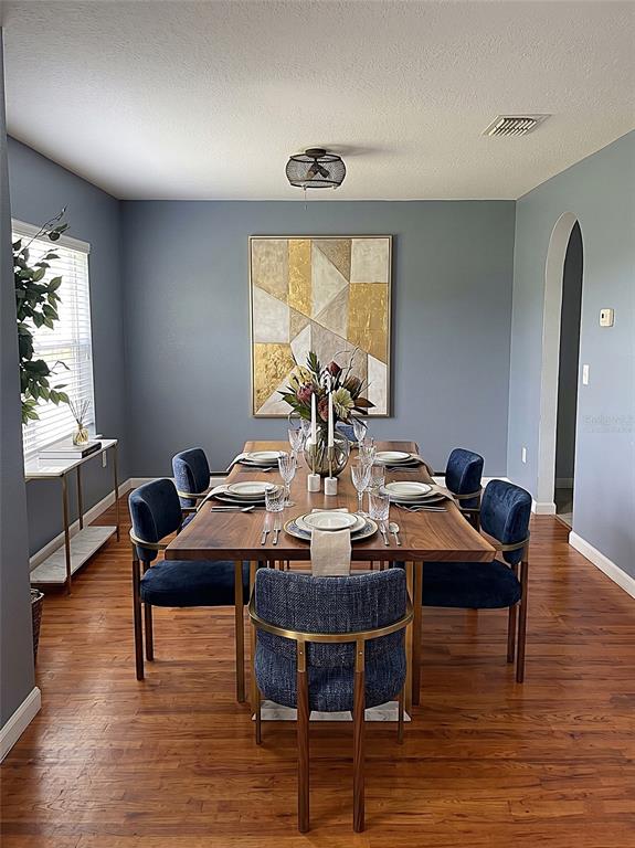 A dining room features a wooden table, blue upholstered chairs, and a large geometric wall art — 321 LAKE HILLS LANE, EAGLE LAKE, FL
