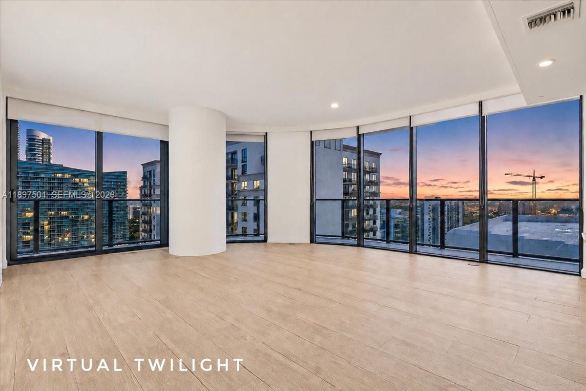 An empty room with light wood floors and floor-to-ceiling windows overlooking a city skyline — 55 SW 9th ST # 3006, Miami FL 33130, MIAMI, FL