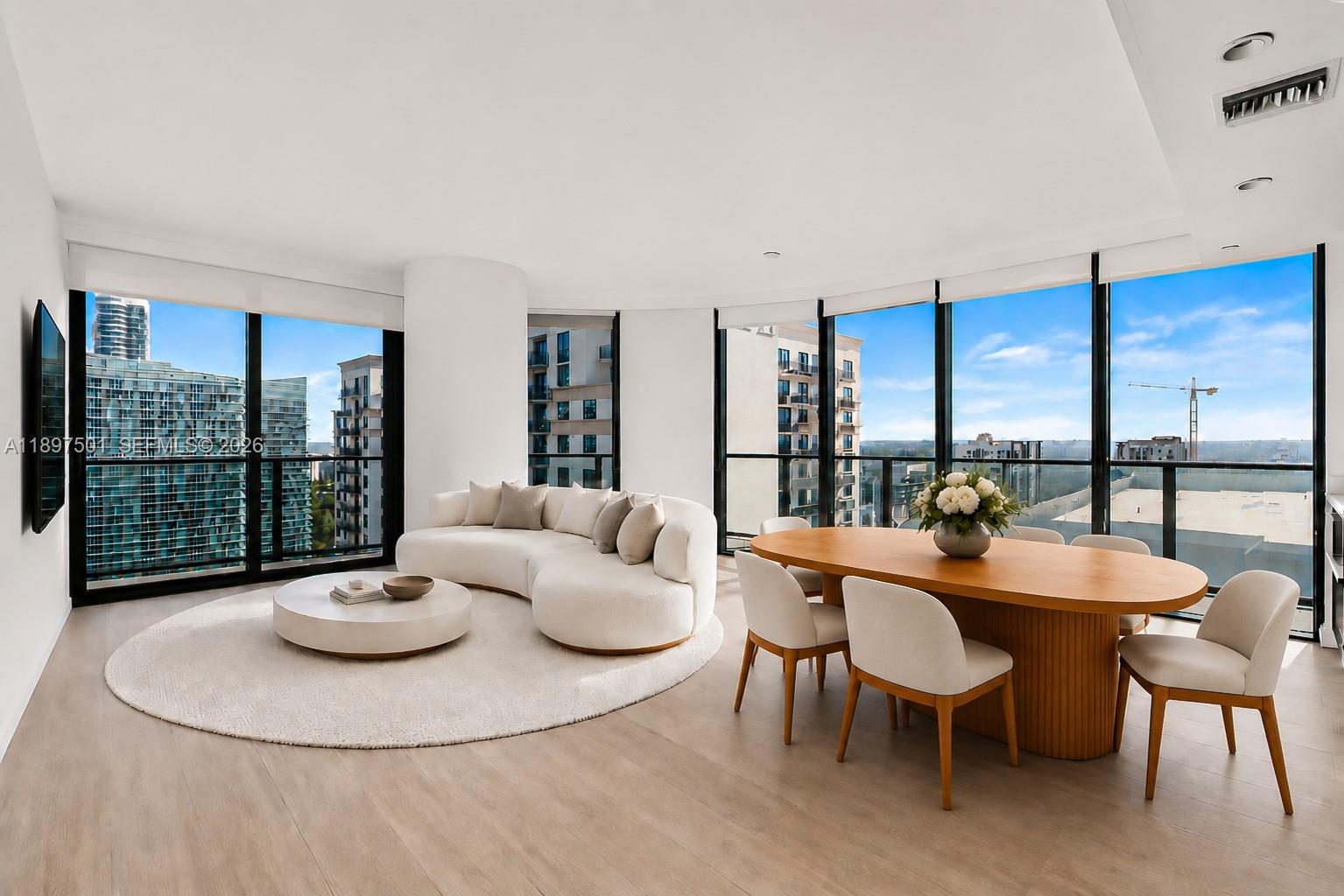 A modern living and dining area features a curved sofa, wooden table, and floor-to-ceiling windows — 55 SW 9th ST # 3006, Miami FL 33130, MIAMI, FL