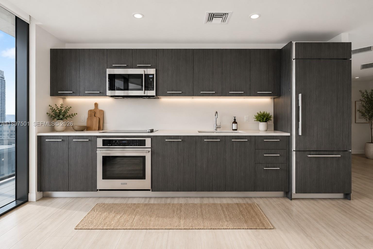 A modern kitchen features dark wood cabinetry, stainless steel appliances, and light-colored countertops — 55 SW 9th ST # 3006, Miami FL 33130, MIAMI, FL