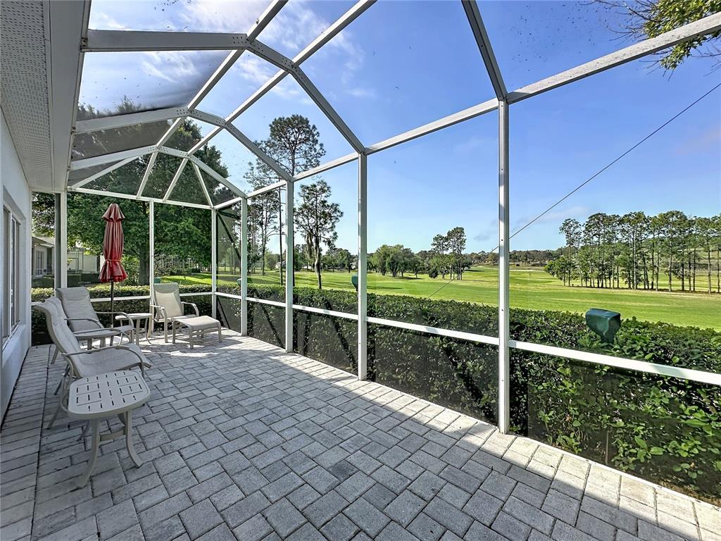 A screened-in patio with paver flooring overlooks a golf course and trees — 3828 AVON COURT, CLERMONT, FL