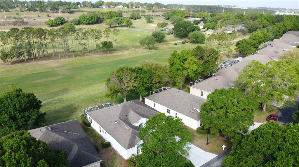 An aerial view of suburban houses with screened lanais bordering a large golf course — 3828 AVON COURT, CLERMONT, FL