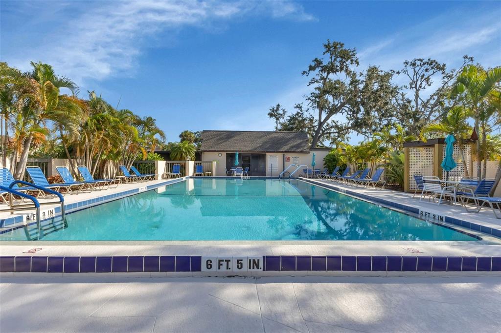 A rectangular swimming pool with lounge chairs on the deck and a building in back — 19505 QUESADA AVENUE UNIT J204, PORT CHARLOTTE, FL