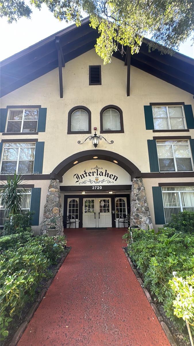 A red walkway leads to the arched entrance of a multi-story building named Interlaken — 3720 Inverrary Dr # 2S, Lauderhill FL 33319, LAUDERHILL, FL