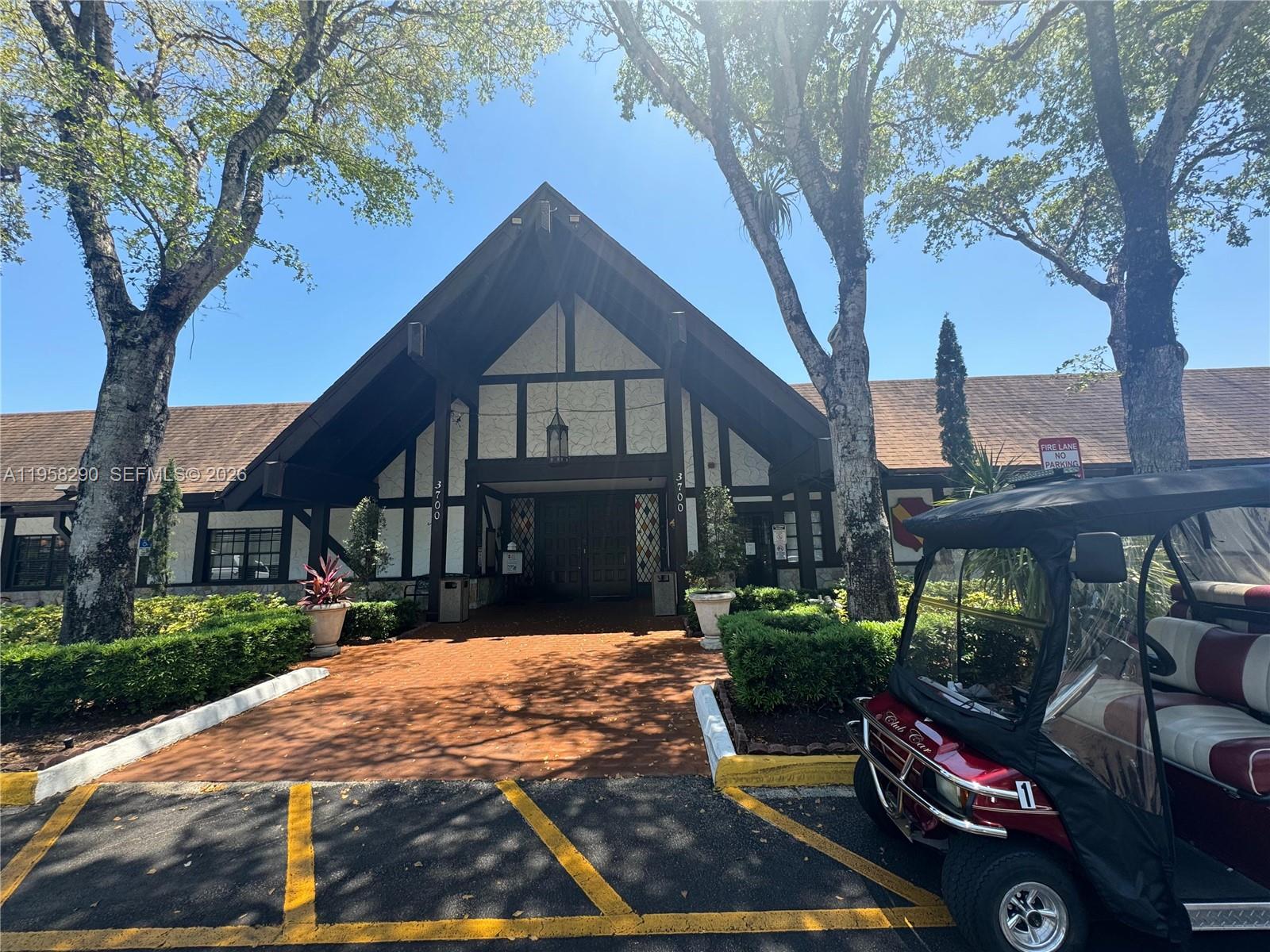 A Tudor-style building entrance features a steep gable roof, dark timber framing, and a golf cart — 3720 Inverrary Dr # 2S, Lauderhill FL 33319, LAUDERHILL, FL