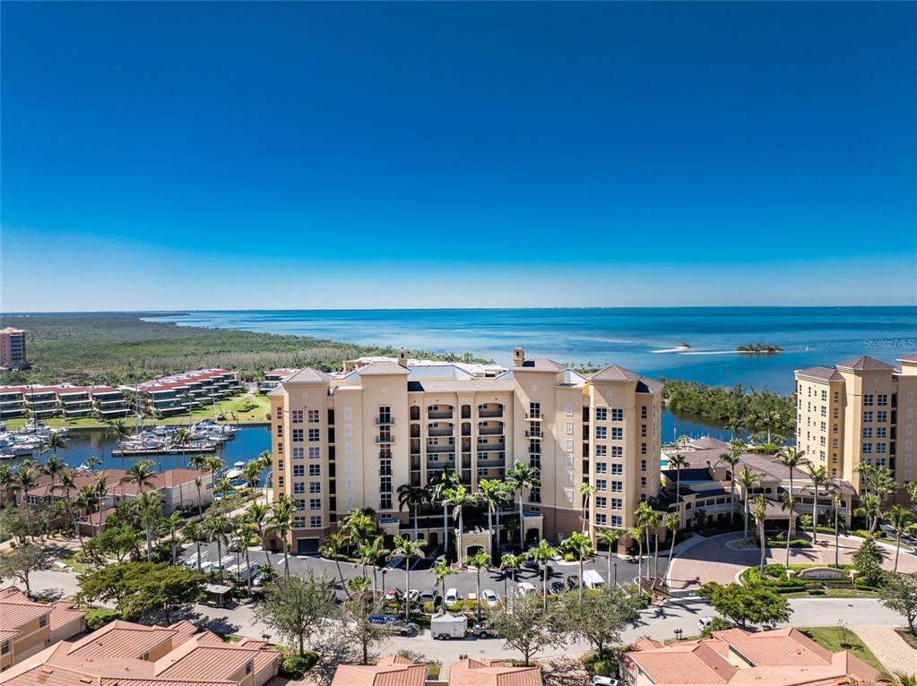 An aerial view shows a large multi-story building complex with a marina and waterfront — 3313 SUNSET KEY CIRCLE UNIT 307, PUNTA GORDA, FL