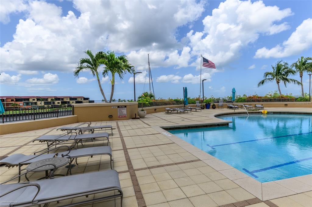 A swimming pool with lounge chairs on a paved deck under a cloudy blue sky — 3313 SUNSET KEY CIRCLE UNIT 307, PUNTA GORDA, FL