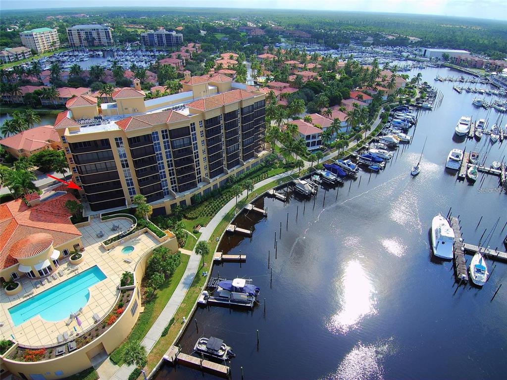 An aerial view shows a multi-story apartment building, a swimming pool, and a boat marina — 3313 SUNSET KEY CIRCLE UNIT 307, PUNTA GORDA, FL