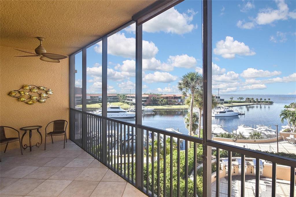 A screened-in balcony with tile flooring overlooks a marina with boats and palm trees — 3313 SUNSET KEY CIRCLE UNIT 307, PUNTA GORDA, FL