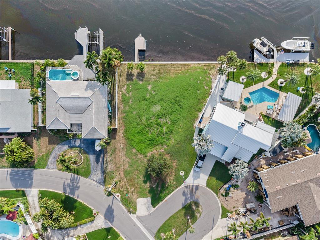 An aerial view shows a vacant waterfront lot situated between two houses with swimming pools — 1301 SEA GULL DRIVE S, ST PETERSBURG, FL