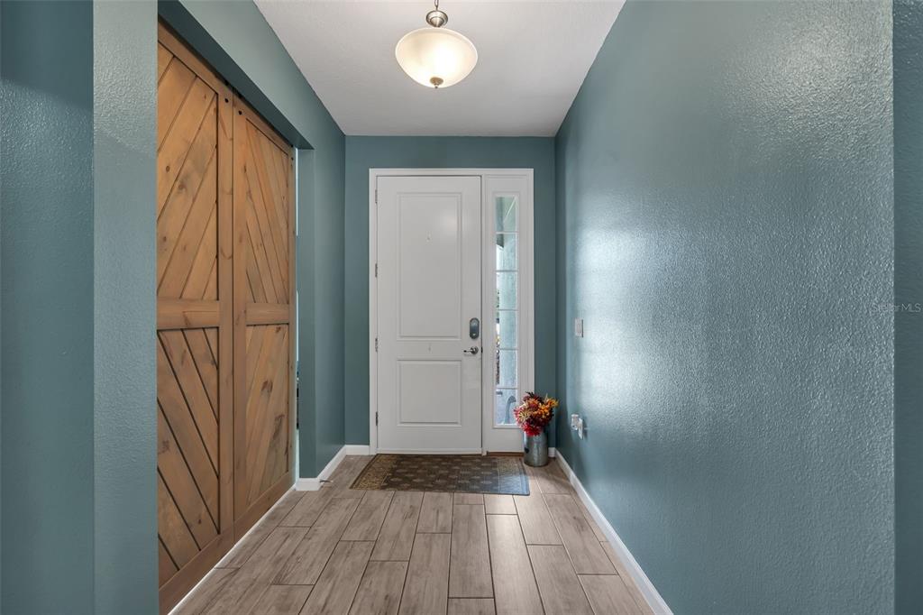 An entryway features teal walls, wood-look tile flooring, a white front door, and sliding barn doors — 822 OPAL COURT, DAVENPORT, FL