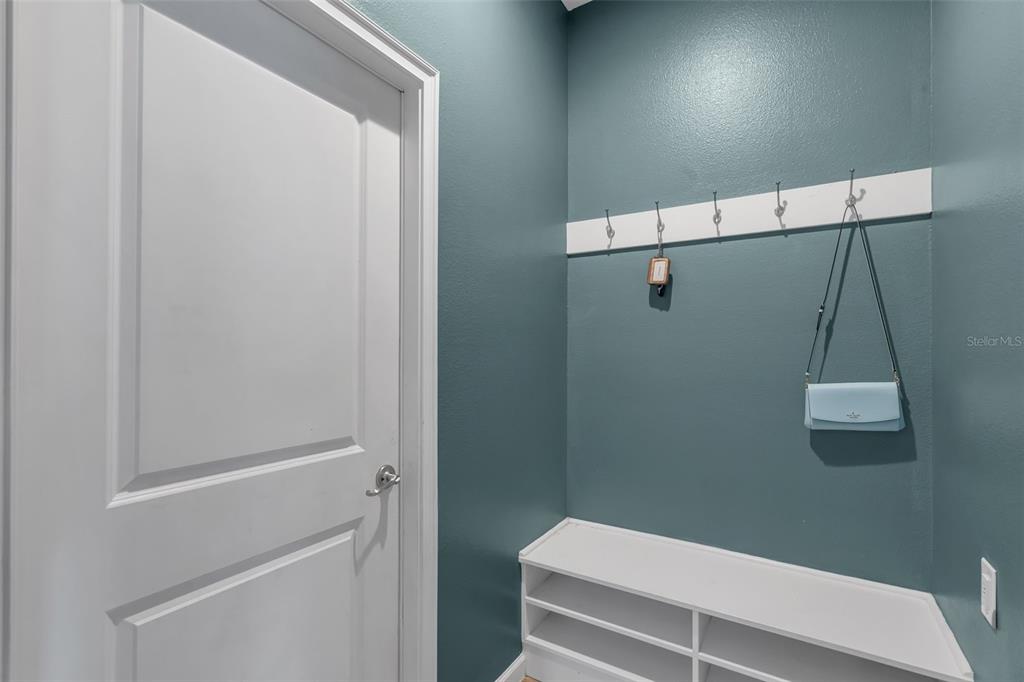 A mudroom features a white bench with shoe storage, wall hooks, and teal-painted walls — 822 OPAL COURT, DAVENPORT, FL