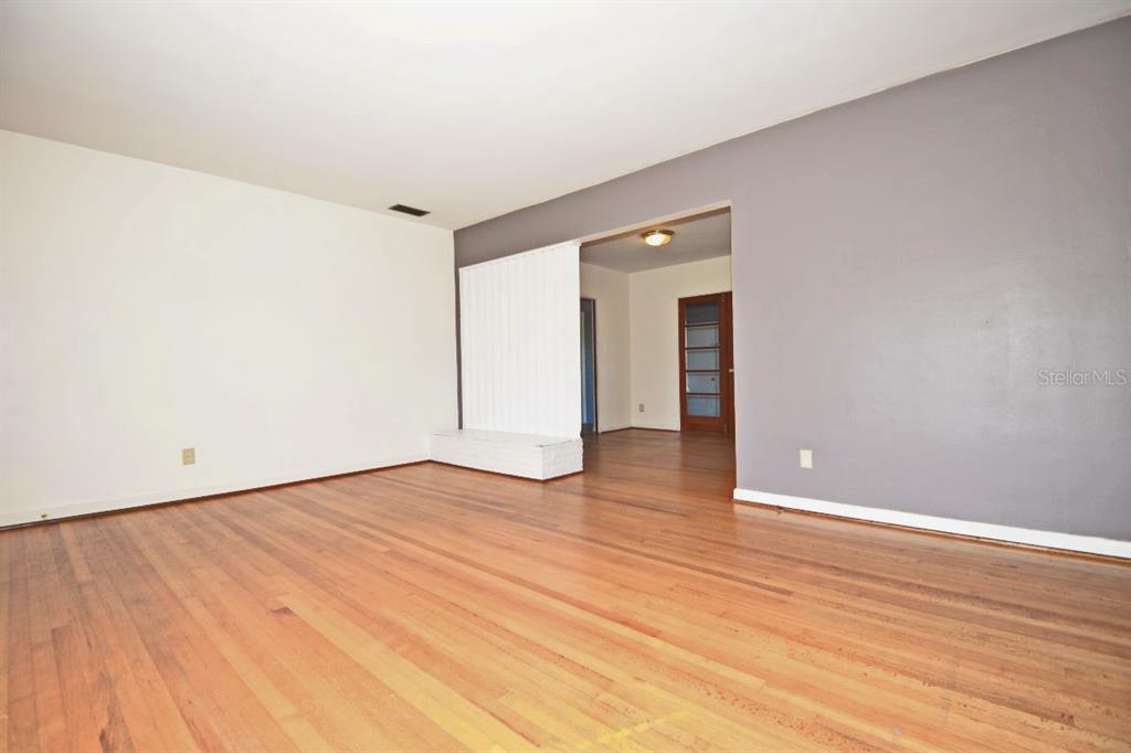 An empty room with hardwood floors, a white accent wall, and a gray wall — 1337 CUMBIE STREET, ORLANDO, FL