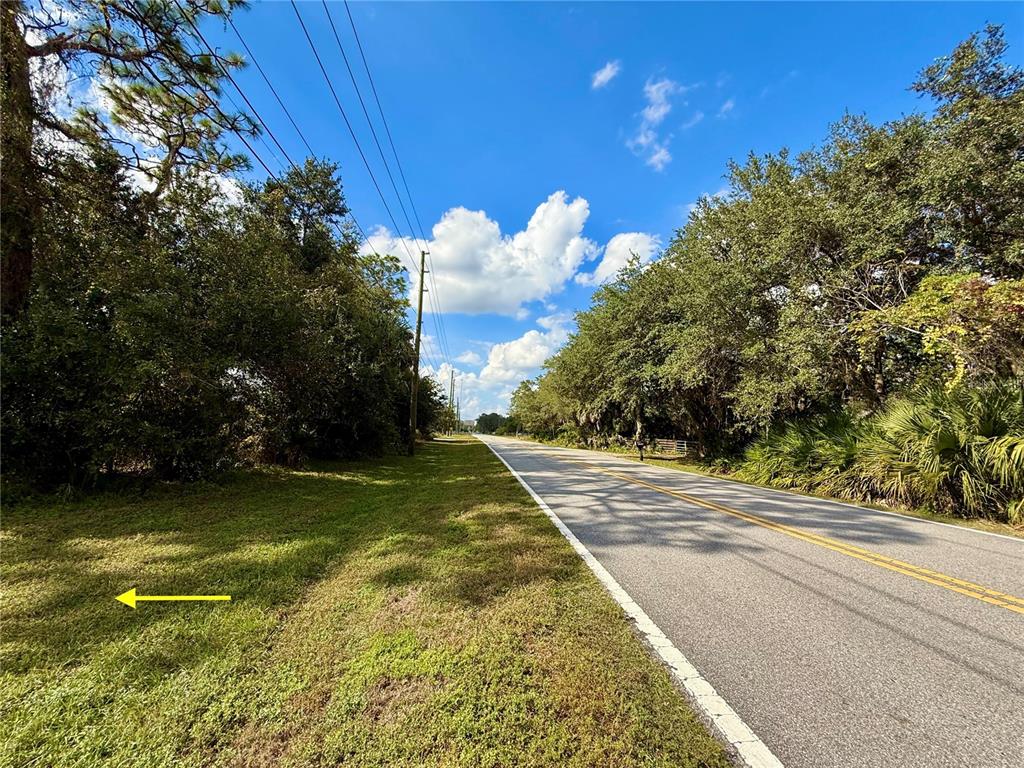A paved road runs alongside a grassy area bordered by trees under a blue sky — LOT 9 FORT CHRISTMAS ROAD, CHRISTMAS, FL