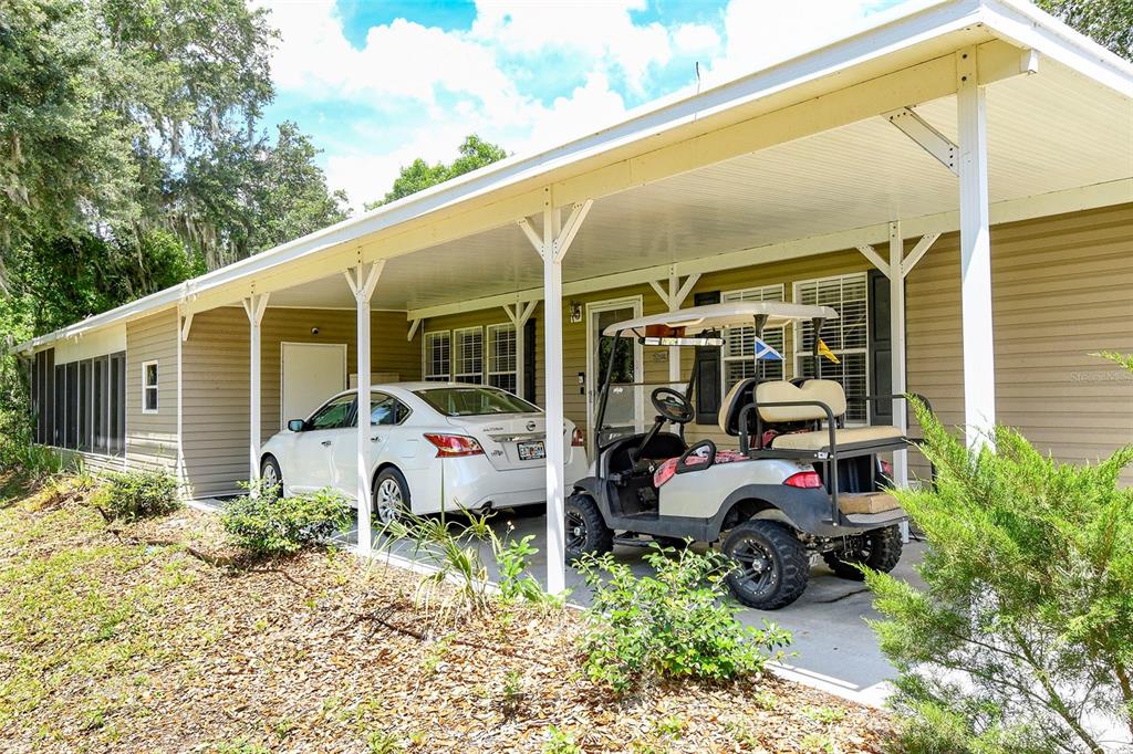 A tan mobile home features a covered carport with a white sedan and golf cart — 11639 MARTELL COURT, LEESBURG, FL