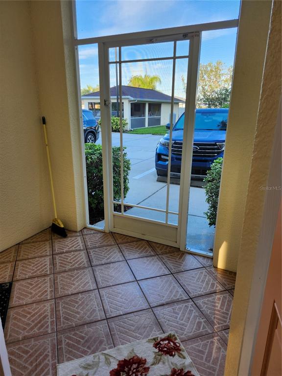 A tiled entryway features a screen door looking out toward a parking area and vehicles — 1216 RIO DE JANEIRO AVENUE UNIT 301, PUNTA GORDA, FL