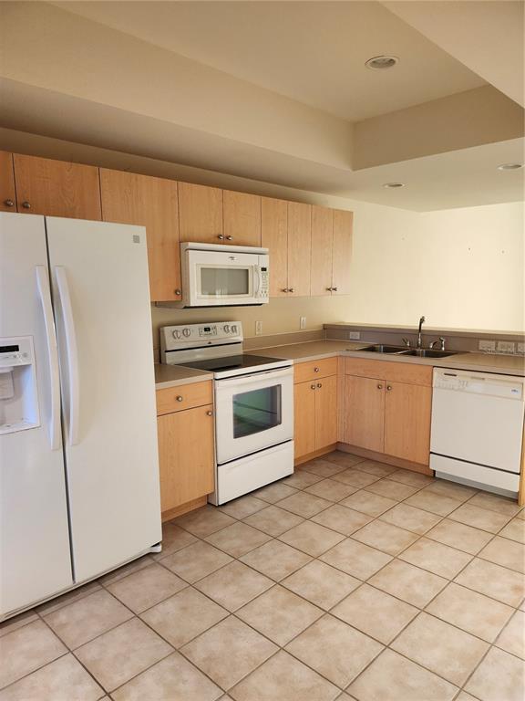 A kitchen features light wood cabinets, white appliances, a tiled floor, and a double sink — 1216 RIO DE JANEIRO AVENUE UNIT 301, PUNTA GORDA, FL