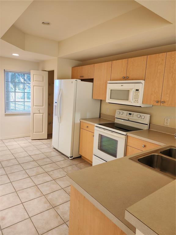 A kitchen features light wood cabinets, white appliances, a tiled floor, and a double sink — 1216 RIO DE JANEIRO AVENUE UNIT 301, PUNTA GORDA, FL