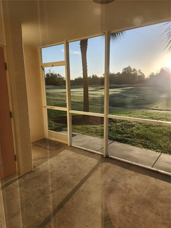 A screened-in porch with a concrete floor overlooks a grassy golf course at sunrise — 1216 RIO DE JANEIRO AVENUE UNIT 301, PUNTA GORDA, FL