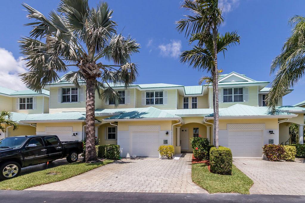 A two-story yellow townhouse with a light green metal roof and two garage doors — 117 Barefoot Cove, Hypoluxo FL 33462, HYPOLUXO, FL
