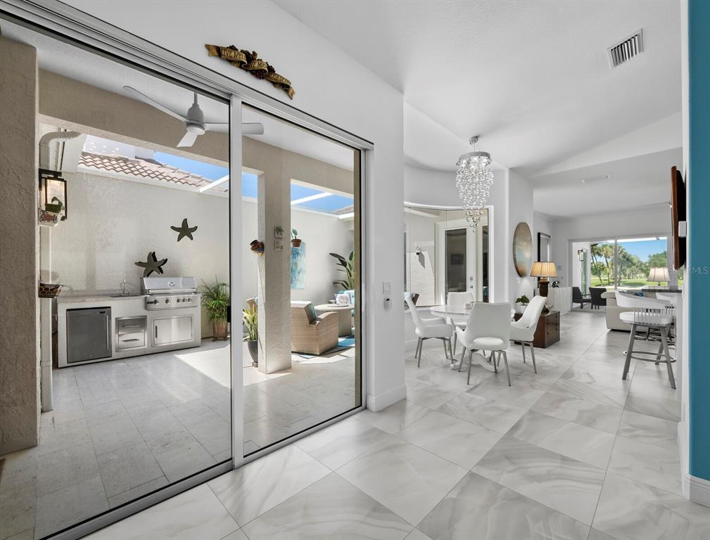 A bright interior dining area connects to an outdoor patio with a built-in grill station — 1914 HARBOUR LINKS CIRCLE UNIT 10, LONGBOAT KEY, FL