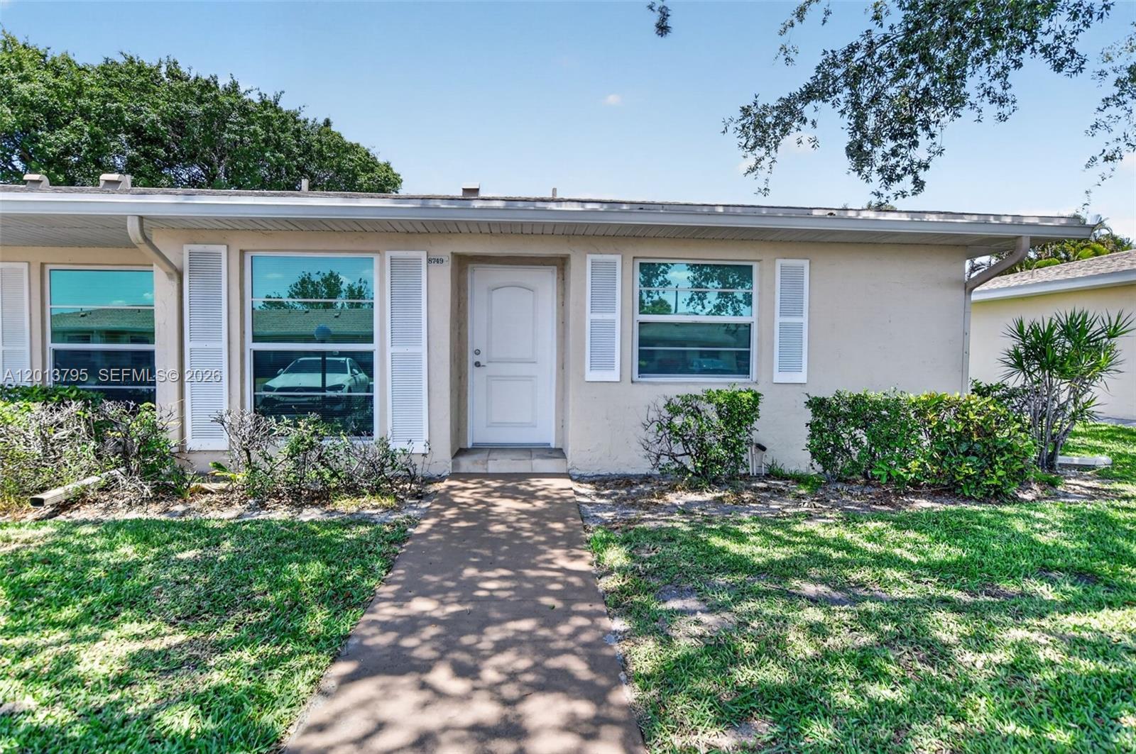 A single-story house exterior features a white front door, shuttered windows, and a concrete walkway — 8749 Belle Aire Dr, Boca Raton FL 33433, BOCA RATON, FL