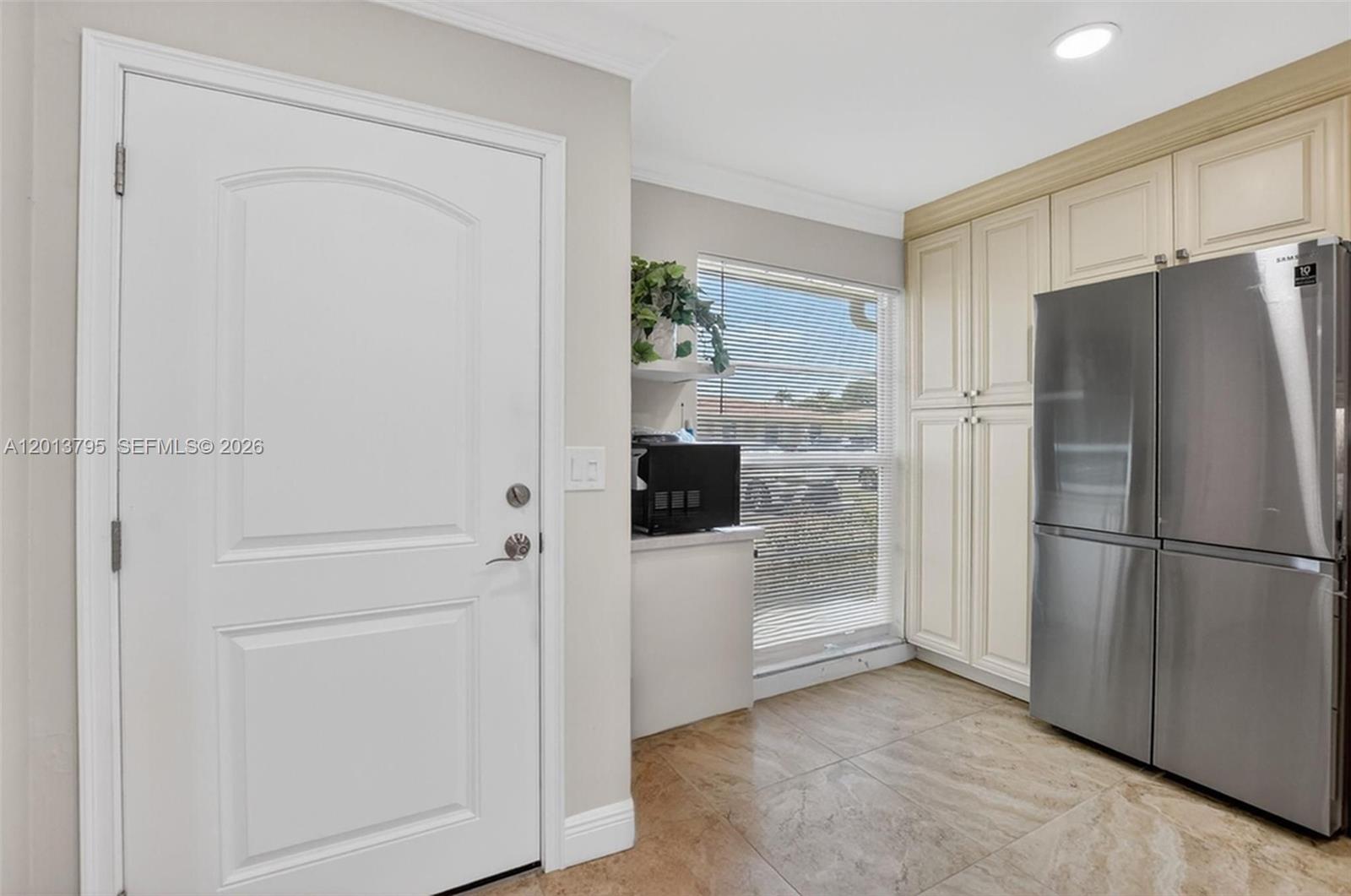 A kitchen features a white door, a stainless steel refrigerator, and light-colored cabinetry — 8749 Belle Aire Dr, Boca Raton FL 33433, BOCA RATON, FL