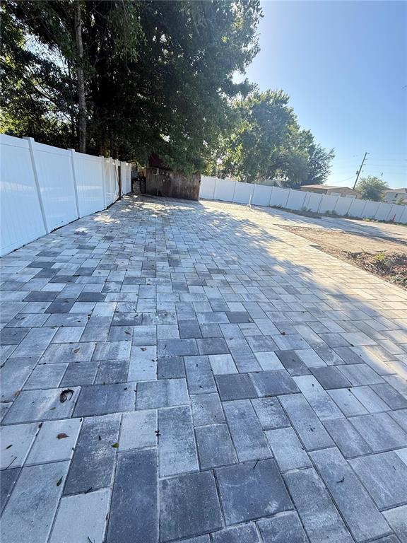 A large paved patio area is enclosed by a white vinyl privacy fence — 19651 CAUSEWAY BOULEVARD, LAND O LAKES, FL