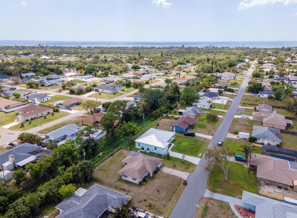An aerial view shows a residential neighborhood with houses, streets, and the ocean in distance — 901 PONDEROSA ROAD, VENICE, FL