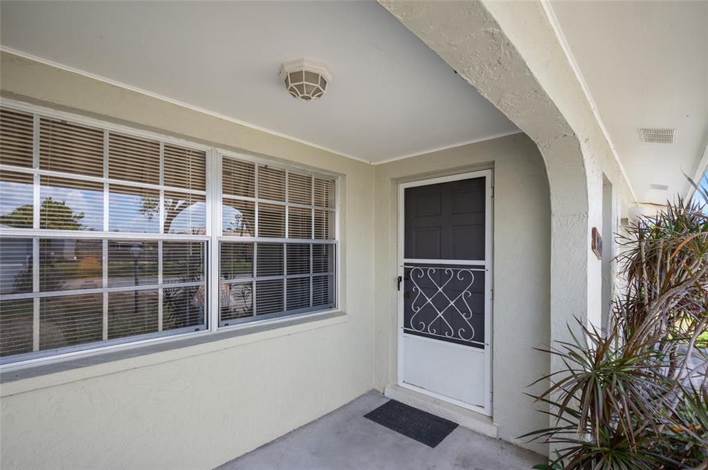 A covered concrete porch features a white storm door, a large window, and a ceiling light — 901 PONDEROSA ROAD, VENICE, FL
