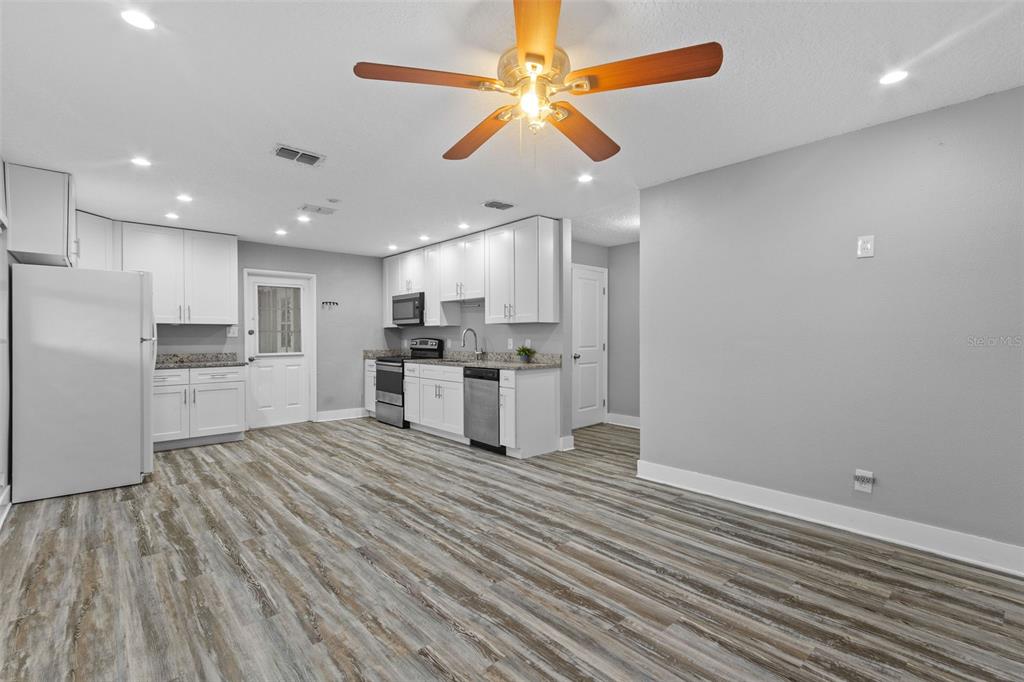 A kitchen with white cabinets, stainless steel appliances, and wood-look flooring in an open room — 4402 W TRILBY AVENUE, TAMPA, FL