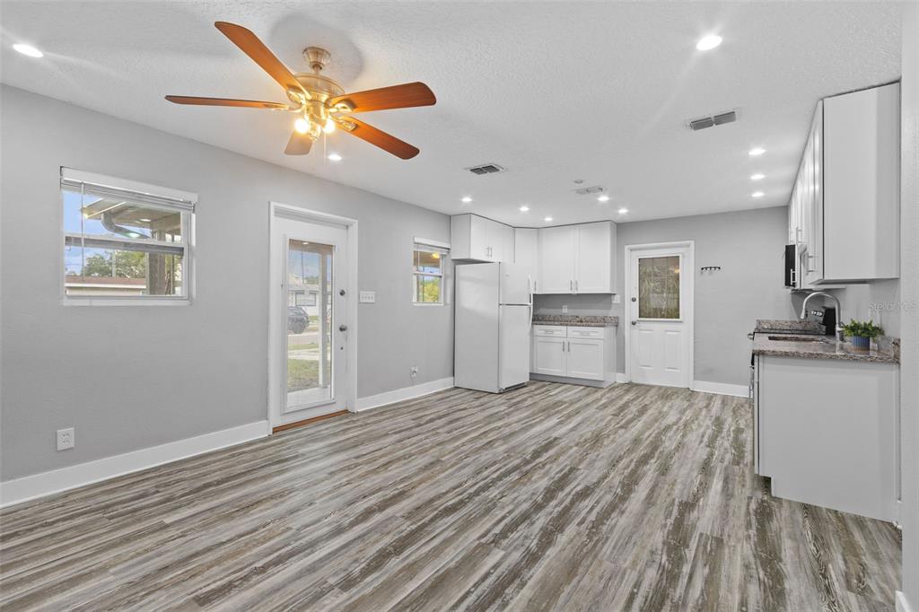 A kitchen and dining area with gray walls, white cabinets, and wood-look flooring — 4402 W TRILBY AVENUE, TAMPA, FL