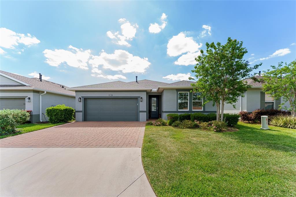 A single-story house with a gray garage, brick driveway, and a green lawn — 5613 NW 40TH LOOP, OCALA, FL
