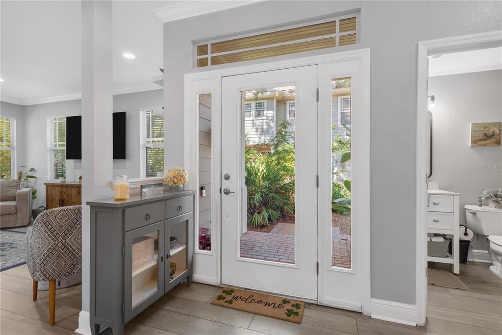 A red front door with sidelights and a transom window sits under a covered entryway — 2852 BAYSHORE TRAILS DR, TAMPA, FL
