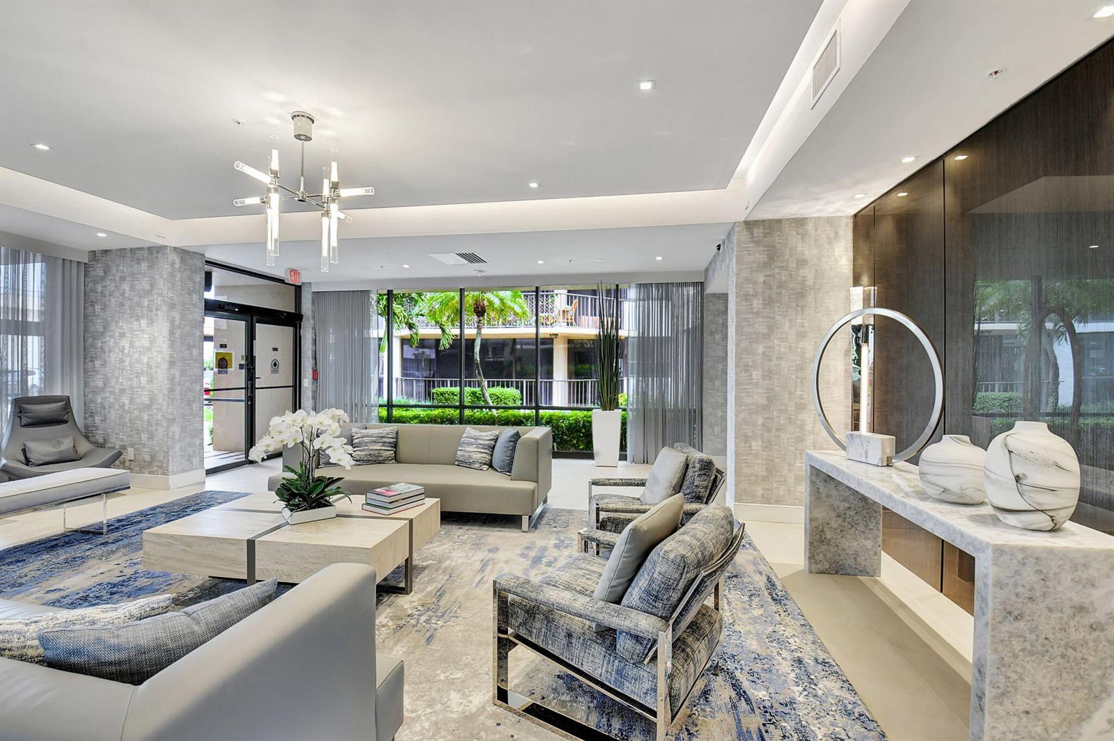 A modern lobby features a seating area with gray furniture, a marble console, and windows — 899 Jeffery Street # 5100, Boca Raton FL 33487, BOCA RATON, FL