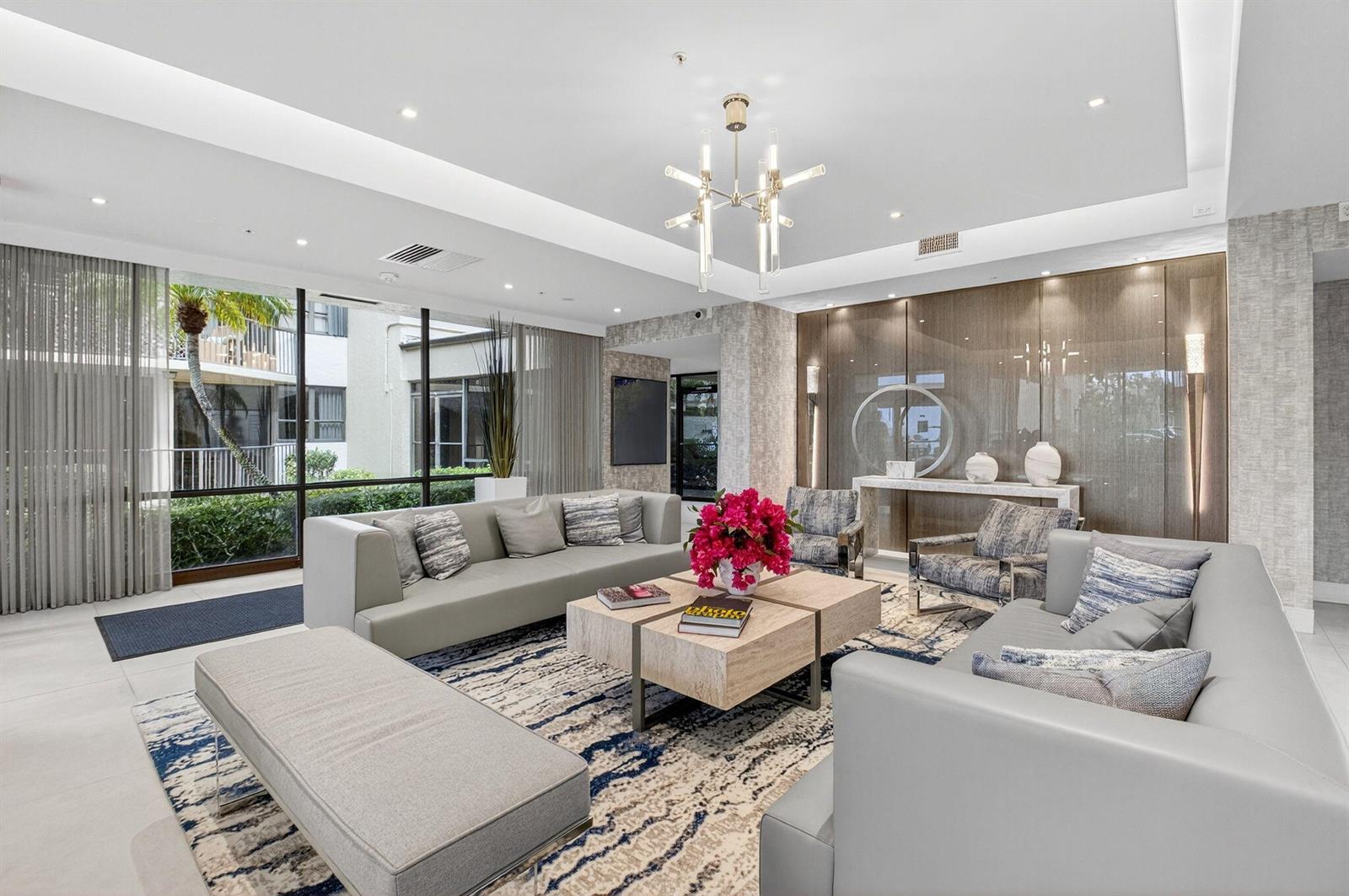 A modern lobby features gray sofas, a central coffee table, and large floor-to-ceiling windows — 899 Jeffery Street # 5100, Boca Raton FL 33487, BOCA RATON, FL