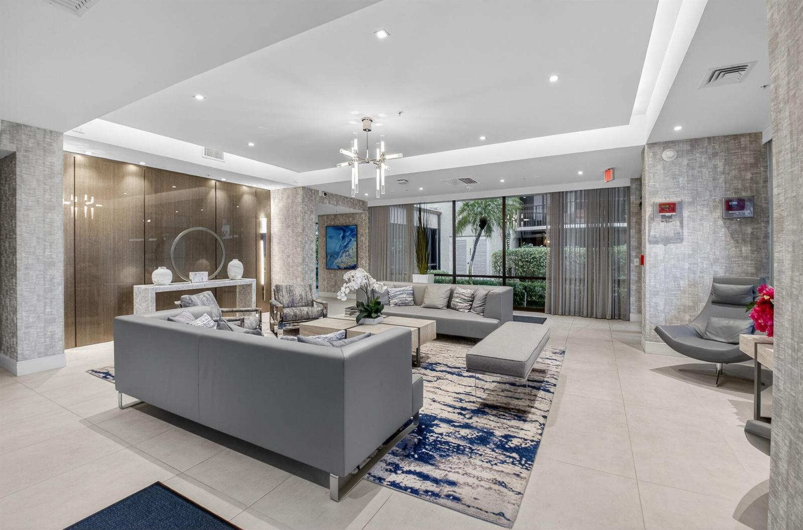 A modern lobby features gray sofas, a patterned area rug, and floor-to-ceiling windows — 899 Jeffery Street # 5100, Boca Raton FL 33487, BOCA RATON, FL