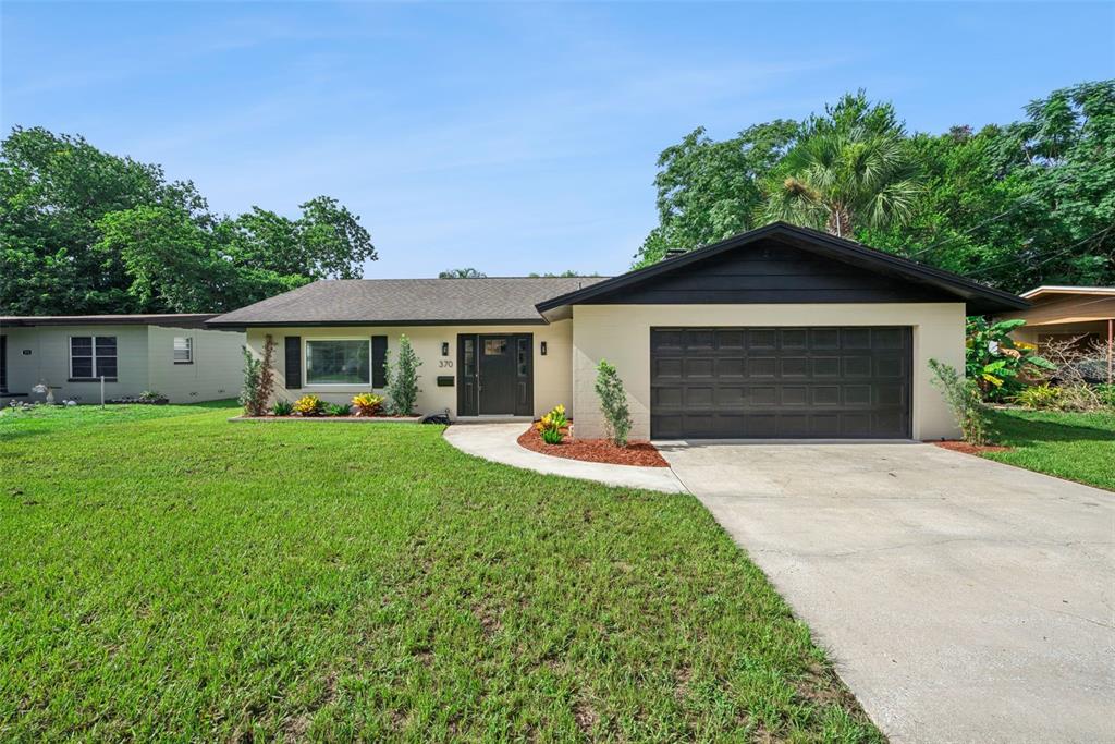 A single-story house with a beige exterior, dark trim, and an attached two-car garage — 370 SULTANA LANE, MAITLAND, FL