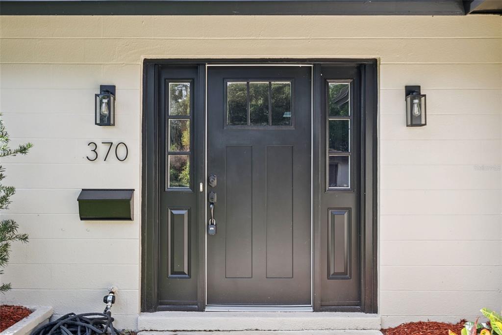 A black front door with sidelights and house number 370 on a beige exterior wall — 370 SULTANA LANE, MAITLAND, FL