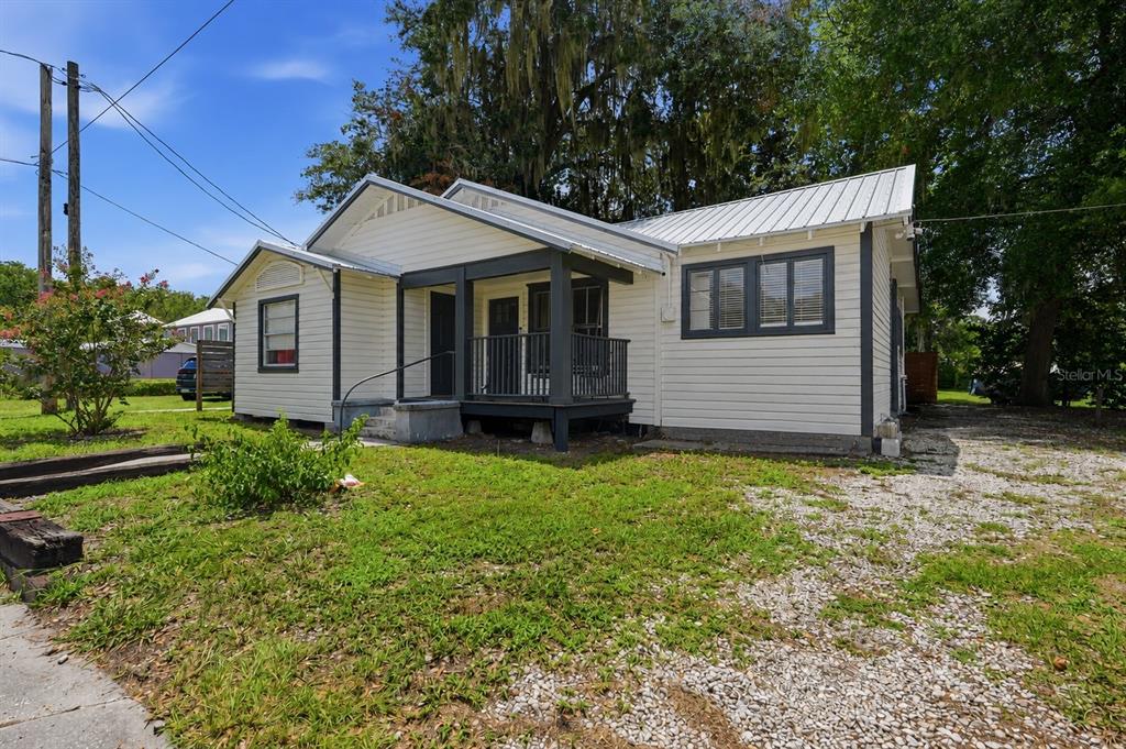A single-story white house with a dark gray porch and a metal roof — 619 NW 7TH AVENUE, GAINESVILLE, FL