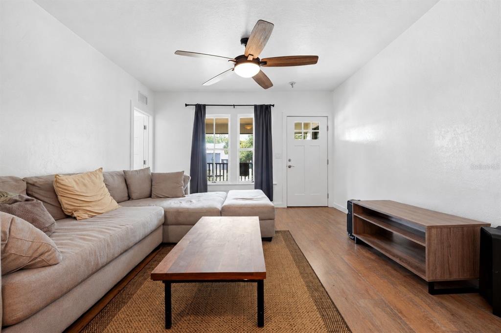 A living room features a sectional sofa, wooden coffee table, media console, and ceiling fan — 619 NW 7TH AVENUE, GAINESVILLE, FL