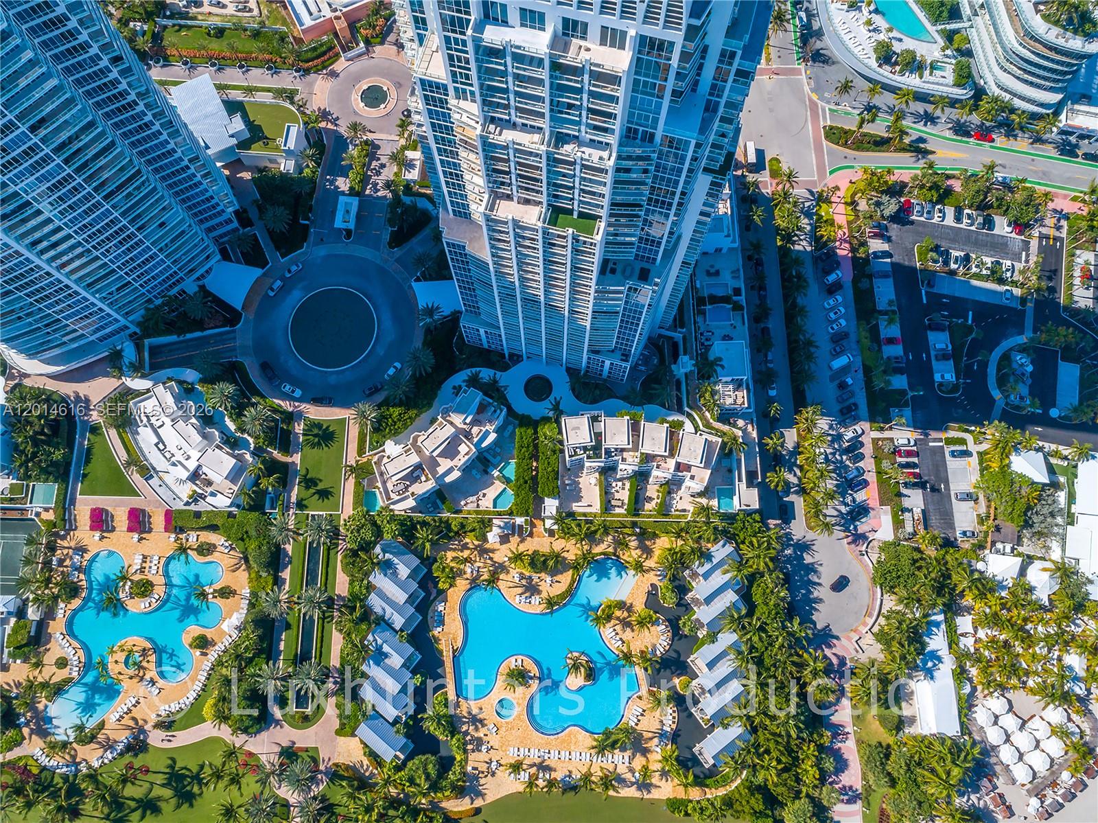 Aerial view of high-rise residential towers, swimming pools, and landscaped grounds — 50 S Pointe Dr # 607, Miami Beach FL 33139, MIAMI BEACH, FL