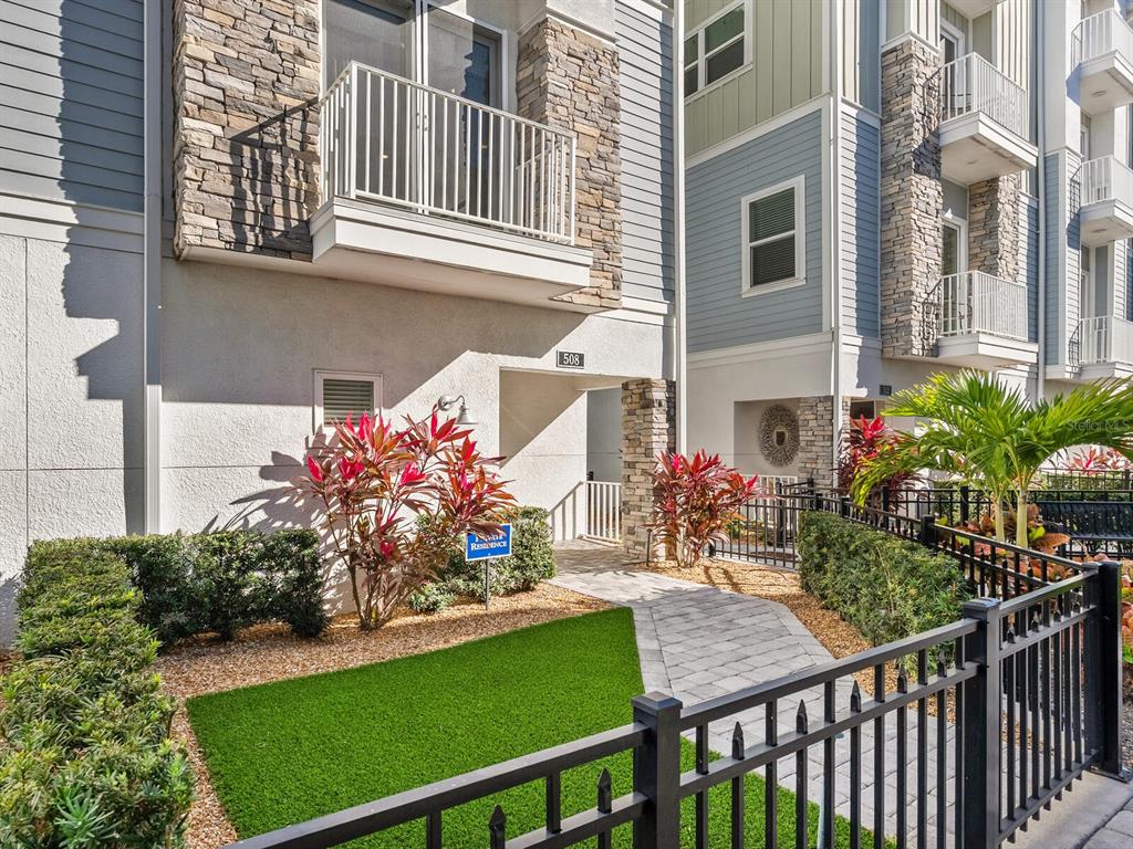 A stone and siding townhouse exterior features a small balcony, walkway, and landscaped front yard — 508 LAUREL PARK DRIVE, SARASOTA, FL