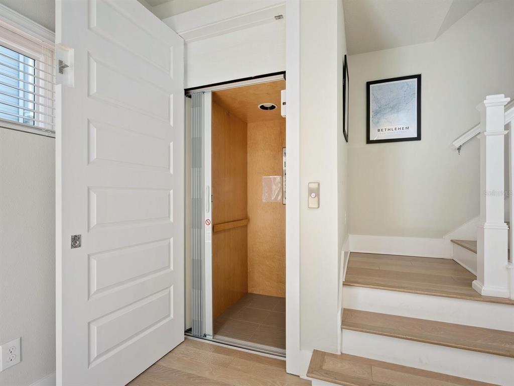 A residential elevator with a wooden interior is positioned next to a staircase — 508 LAUREL PARK DRIVE, SARASOTA, FL