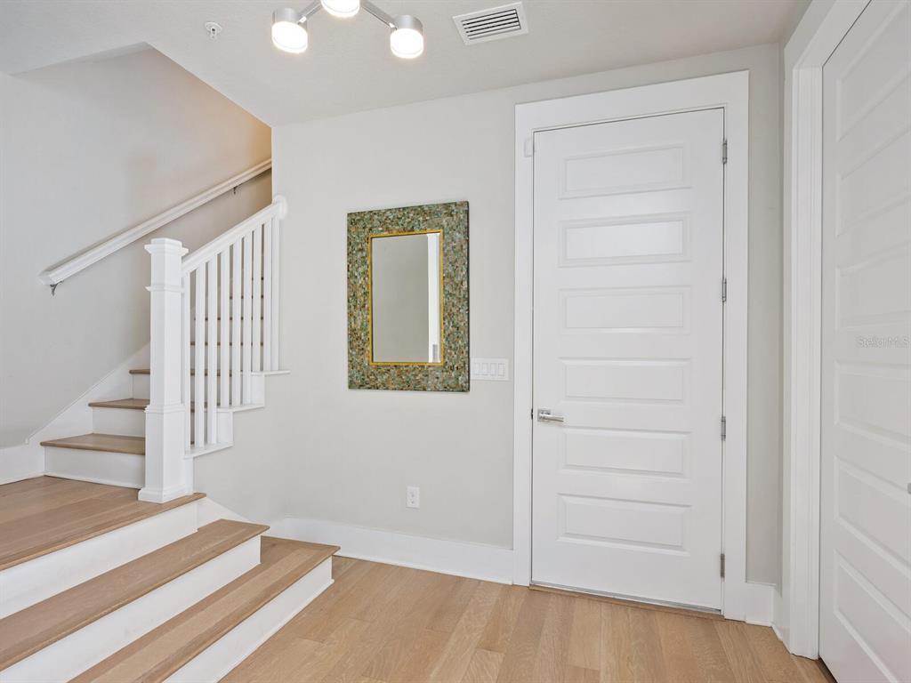 A staircase with light wood steps and a white railing stands beside a white door — 508 LAUREL PARK DRIVE, SARASOTA, FL
