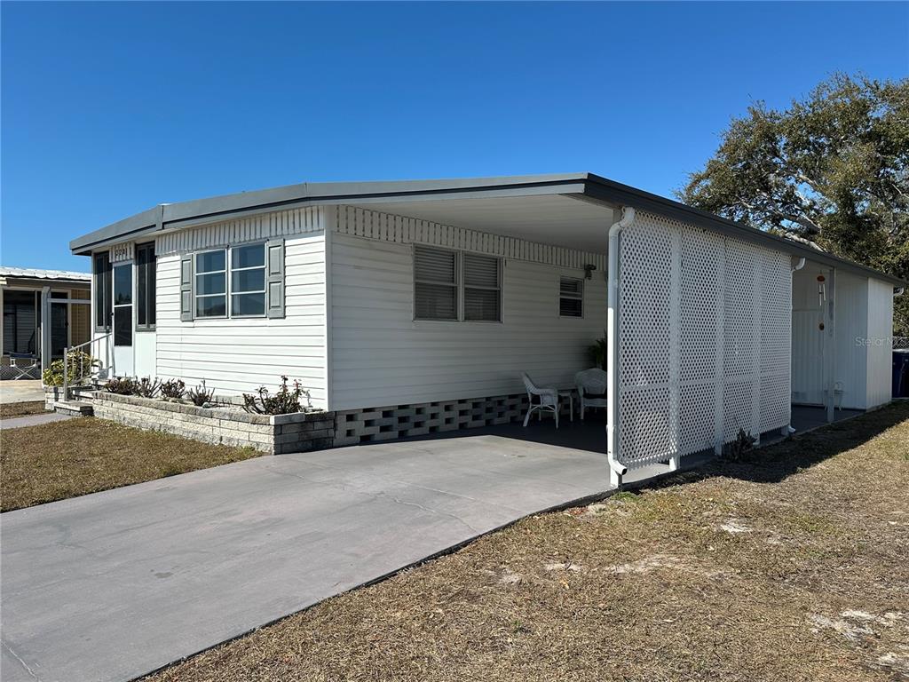 A white mobile home features a concrete driveway, a carport, and a lattice privacy screen — 5619 BAYSHORE ROAD UNIT 328, PALMETTO, FL
