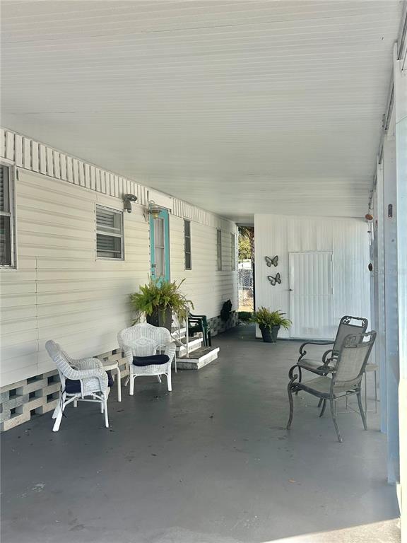 A covered carport area features a white mobile home exterior, seating, and a storage shed — 5619 BAYSHORE ROAD UNIT 328, PALMETTO, FL